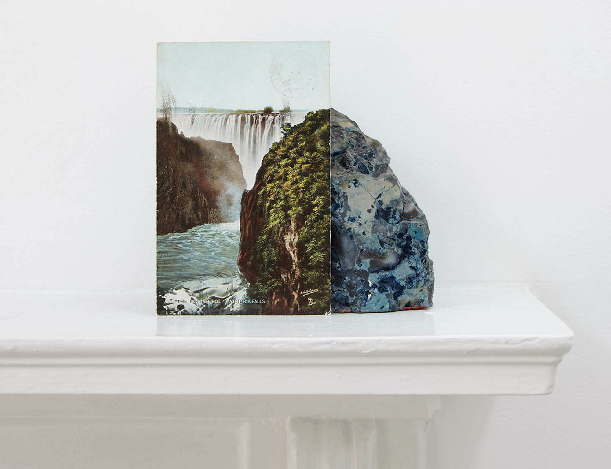 Image: Stuart Whipps, A postcard of Victoria Falls leaning against a geological sample from John Latham's mantlepiece, C-Print, 31.25cm x 25cm, 2013 (John Latham at 100: African Incidentalism 0)